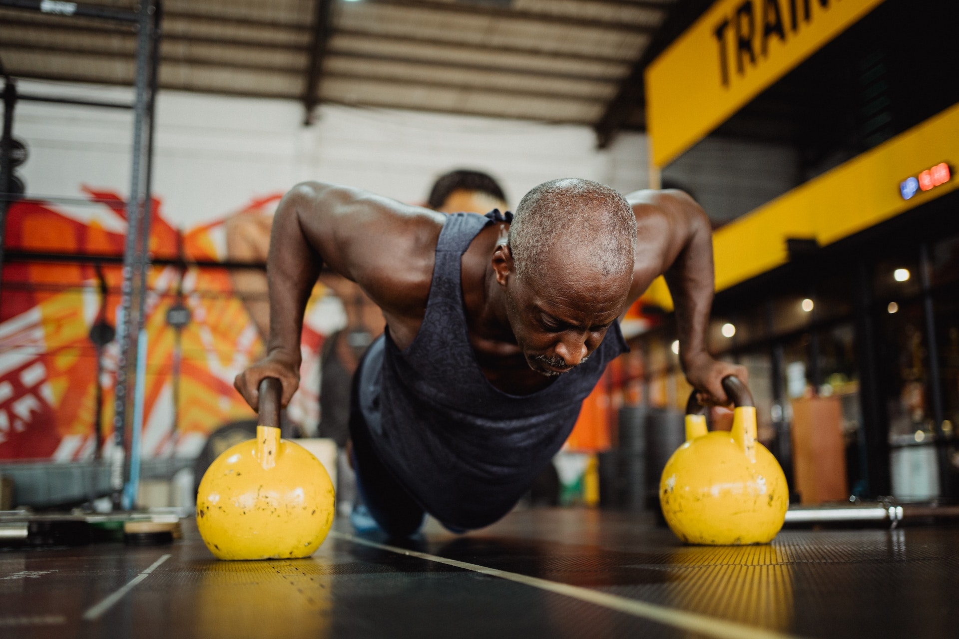 man doing push-ups using yellow kettlebell